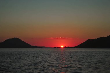 Deniz güneş ışığı akşam arka plan üzerinde güzel gün batımı. Tropik Komodo adasında Güzel Gün Batımı, Labuan Bajo, Fores, Endonezya