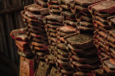 Üst üste istiflenmiş kırmızı kil kiremit yığını.