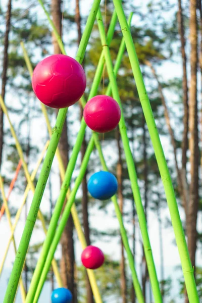 colorful hanging balls over rope wooden ladder in adventure park in forest