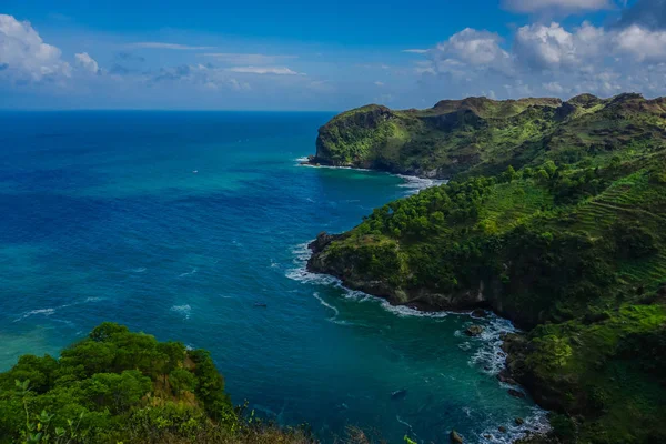 View of landscape ocean and nice green hill on white clouds and Blue sky background. Kebumen, Central Java, Indonesia