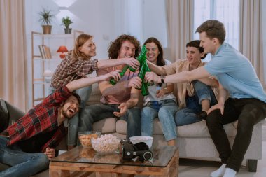 Oturma odasında aydınlık bir evde arkadaşlar çok etnik çocuklar büyük bir şirket bir futbol maçı izlerken ve en iyi takım bayanlar zaferini kutluyor