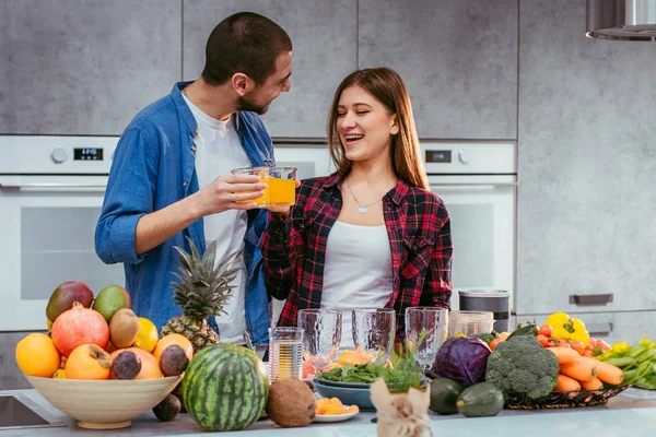 Retrato de jovem casal feliz na cozinha cozinhar juntos beber suco de laranja pela manhã em casa — Fotografia de Stock