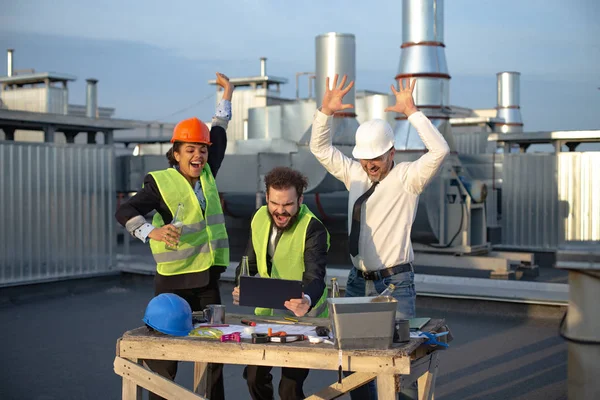 Tutti e tre i bei lavoratori bevevano birra mentre guardavano il video sul tablet, la loro gioia riempiva l'atmosfera mentre celebravano il loro successo. — Foto Stock