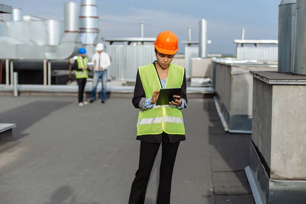 Sul tetto del cantiere bellissimo ingegnere africano fare una conversazione con qualche lavoratore utilizzando il tablet . — Foto Stock