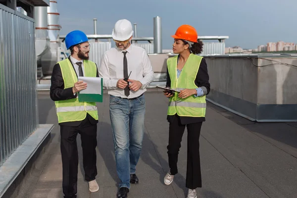 İnşaat endüstrisinden bir grup mühendis ve mimar, genç bir işadamıyla tablet ve çarşaflardan inşa planlarını inceliyor.