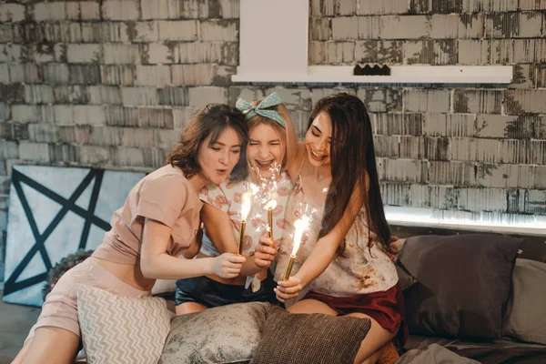 Teenager ladies best friends have a pajamas party they using a sparkling fireworks, young ladies have a good time together, home lifestyle party