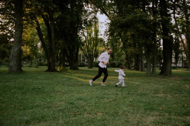Baba ve oğul yeşil sahada oynamak, koşmak ve eğlenmek
