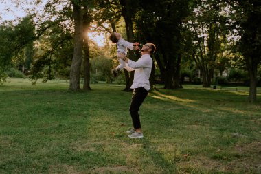 Gün batımında baba parkta oynayan küçük oğlu ile el ele oğlunu alarak ve zaman zevk , onlar şık giysiler giyiyor