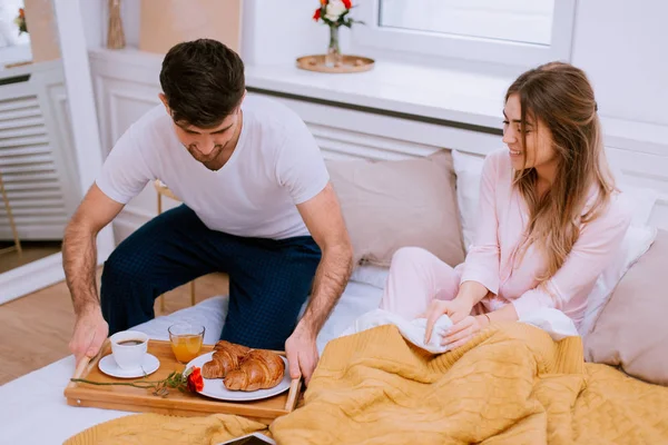 O amante traz um café da manhã para sua namorada, surpreendendo-a no dia dos amantes, ela está muito feliz — Fotografia de Stock