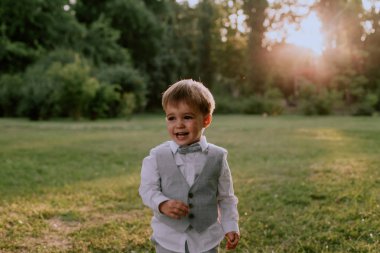 Yeşil bir parkın ortasında, küçük bir çocuk gülümsüyor ve çok mutlu.