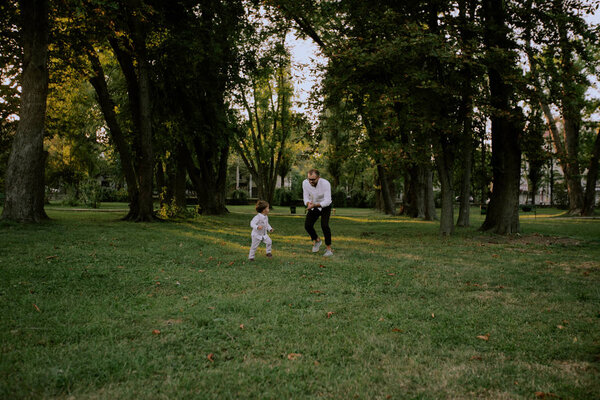 Father and son play on the green field, run and have fun