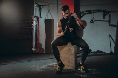Profesyonel bir bandaj kullanarak konsantre çekici adam spor salonunda eğitim başlamak için hazırlanıyor ellerini sarar