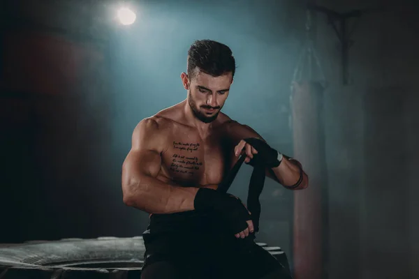 Ayrıntılar closeup vücut geliştirme kavramı adam profesyonel bir bandaj ile spor salonunda eğitim için hazırlanıyor ellerini sarar