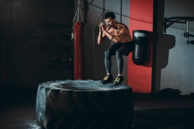 Vücut geliştirme çekici çocuk sıkı çalışıyor. Büyük lastiğe atlıyor. Çapraz fitness sınıfında çok tatlı oluyor.