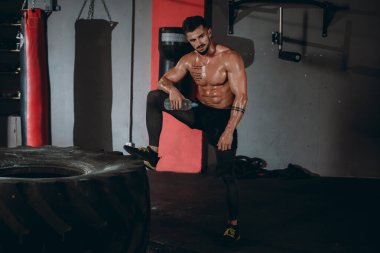 Kameranın önünde poz veren profesyonel vücut geliştirme uzmanı spor salonunda büyük kaslarını gösteriyor.