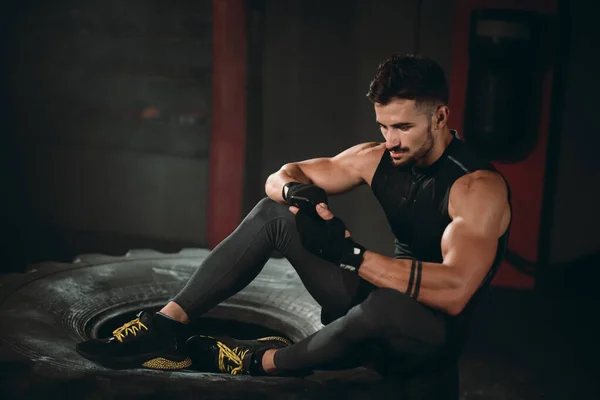 En un estudio oscuro gimnasio atlético hombre carismático después de su entrenamiento tomar el teléfono inteligente mirando a través del teléfono — Foto de Stock