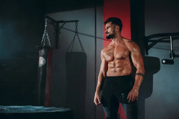 Posando musculação homem mostra seu músculo em um estúdio preto na frente da câmera vestindo sportswear profissional — Fotografia de Stock