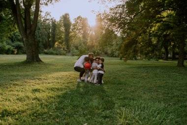 Parkın ortasında çok sevimli sarılma üç çocuk ile çok güzel aile dostu birlikte çok şık giysiler giyen zaman harcama zevk