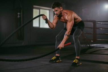 Onun egzersiz yaparken o konsantre yüz yapmak çapraz fit eğitim pratik halatlar atletik adam ile sert egzersizler
