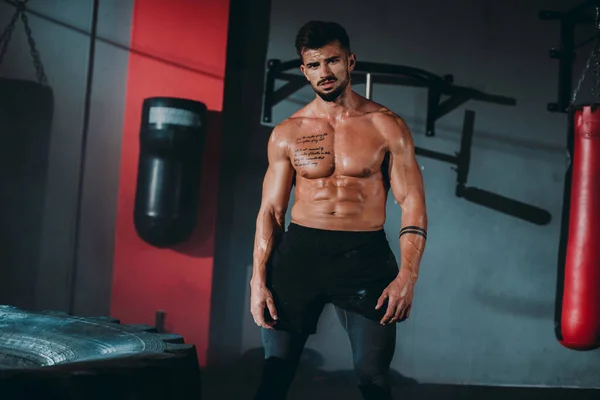 Homem de musculação profissional posando na frente da câmera mostrando seu grande músculo em uma aula de fitness cruzada — Fotografia de Stock