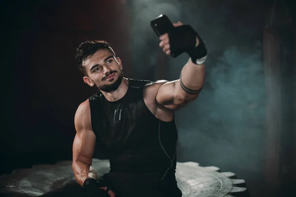 Homem atlético carismático sorridente tirar selfies com seu smartphone após o treino duro em uma aula de fitness cruz — Fotografia de Stock