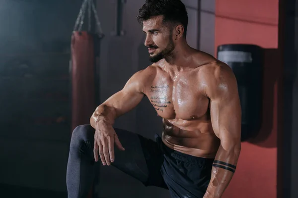 Posierender Bodybuilding-Mann zeigt seine Muskeln in einem schwarzen Studio vor der Kamera in professioneller Sportbekleidung — Stockfoto