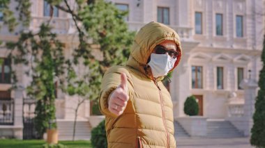 Korumacı maskeli boş bir sokak adamının ortasında insanlara koruyucu maske takmadan sokakta yürümemelerini önerirken Coronavirus...