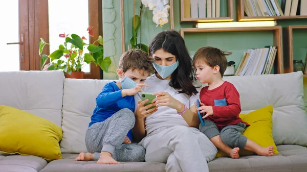 Na sofie matka z dziećmi w masce ochronnej pozostają w domu i za pomocą smartfona do gry mały chłopiec nie nosić maski ochronnej kwarantanny czas nowy Coronavirus 2019 — Zdjęcie stockowe