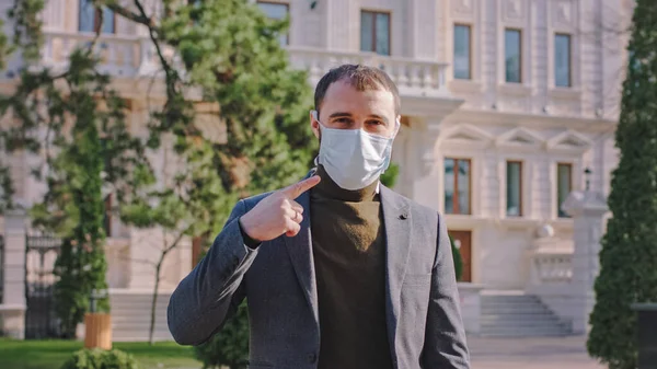 W środku pustej ulicy człowiek w masce ochronnej sugerując ludziom nosić maskę, aby zatrzymać chodzenie po ulicy bez maski ochronnej, podczas gdy jest koronawirusem — Zdjęcie stockowe
