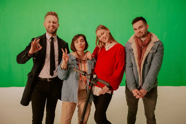 Grupa ludzi w zielonym studio jest szczęśliwa i patrzy w kamerę. — Zdjęcie stockowe