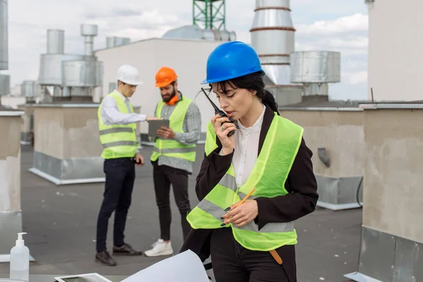 No telhado do canteiro de obras engenheiro bonito fazer uma conversa com algum trabalhador usando a ração — Fotografia de Stock