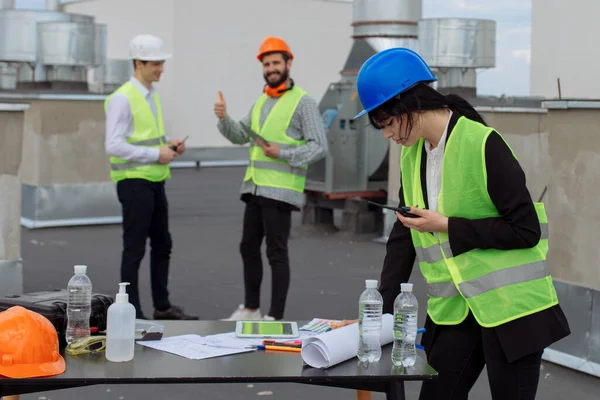 No telhado do canteiro de obras engenheiro bonito fazer uma conversa com algum trabalhador usando a ração — Fotografia de Stock