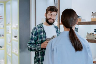 Modern ayakkabı mağazası yakışıklı müşterisi onun için en iyi ayakkabıları bulmaya çalışıyor Asyalı kadın mağazasındaki satıcıyla konuşuyor.