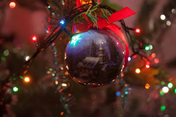 Bir Noel ağacı ve çelenk arka planda bir evin resmi ile bir Noel topu Fotoğrafı.