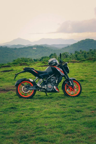 Una moto deportiva naranja descansando en una colina verde — Foto de Stock