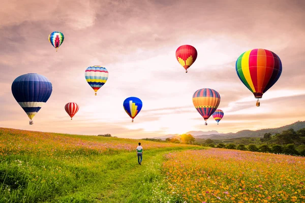 Asyalı adamın günbatımı üzerinde uçan sıcak hava balonu ile evren çiçekler üzerinde ayakta kontrast.