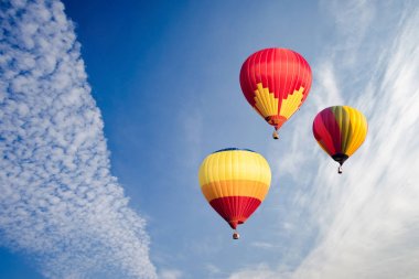 Beyaz bulutlar ve mavi gökyüzü üzerinde uçan renkli sıcak hava balonları