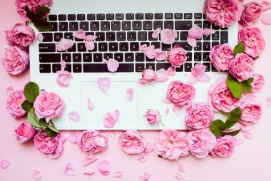 Kartpostal şablonu. Laptop klavyesi pembe güllerle dolu, pembe arka planda tomurcuklar. Üst Manzara. Düz yatıyordu. Şenlik arka planı. Sevgililer Günü