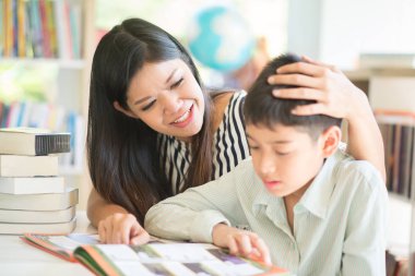 Küçük çocuk ve annesi kütüphanede kitap okuma 