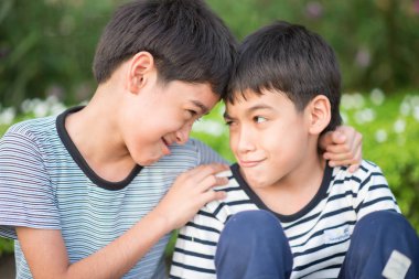 Asain kardeş çocuk oturup birlikte parkta