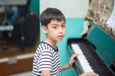 Asyalı küçük çocuk oynamak Piyano çalışma müzik sınıf