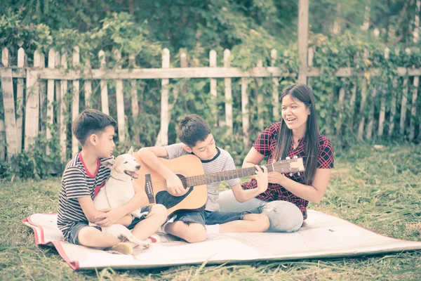 Single mom and sons play guitartogether with fun  in the park