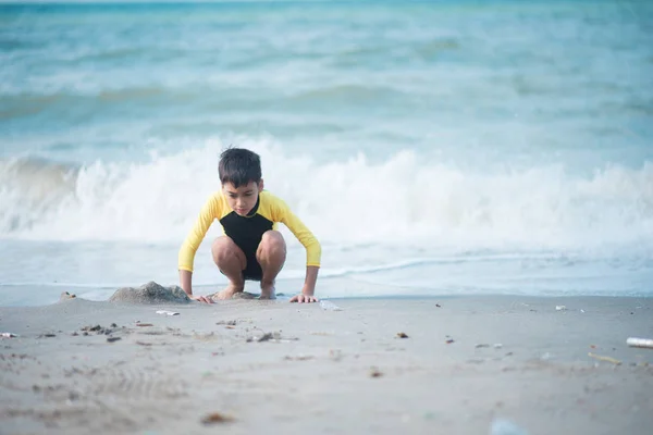 ビーチで波と砂を弾いている少年 — ストック写真