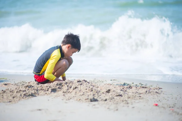 男孩在海滩上玩波浪和沙子 — 图库照片