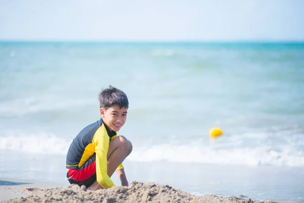 ビーチで波と砂を弾いている少年 — ストック写真