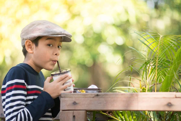 Küçük çocuk yeşil café'de çikolatalı süt içme