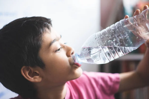Little boy drinking water in the room with happy face