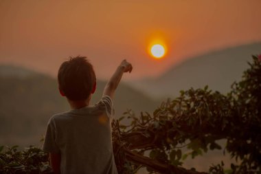 Tepenin arkasında gündoğumu sabah isteyen küçük çocuk