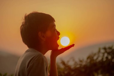 Tepenin arkasında gündoğumu sabah isteyen küçük çocuk