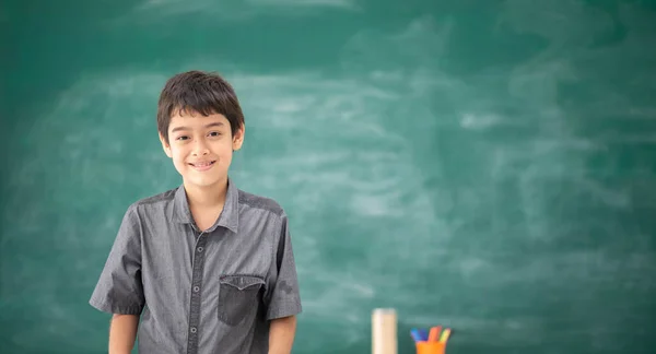 学校の教室で黒板の前に立っているアジアの学生少年 — ストック写真
